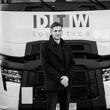 Kierownik działu floty DTW Logistics stoi przed ciągnikiem siodłowym DTW Logistics Group